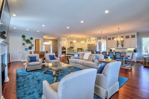 A spacious living room with a blue rug, white sofas, and a glass coffee table. - 5BR Lakefront home - Dock, 2 kitchens, pool table (Hot Springs)