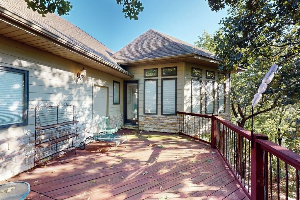 A house with a covered porch, a stone wall, and a red railing.