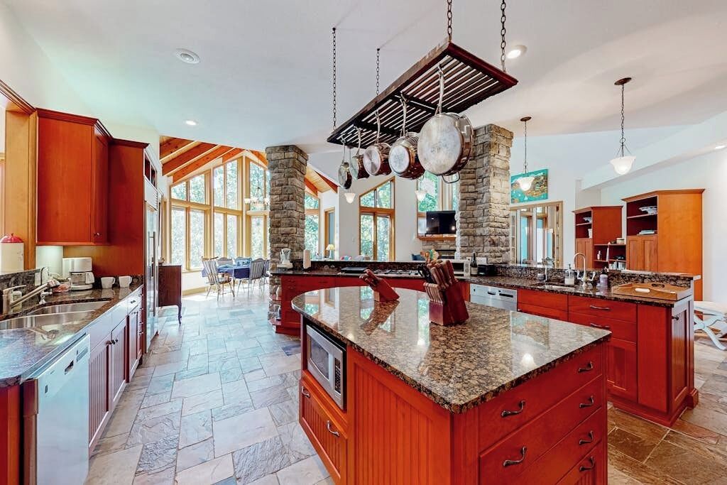 A spacious kitchen with granite countertops, a large island, and a stone accent wall.