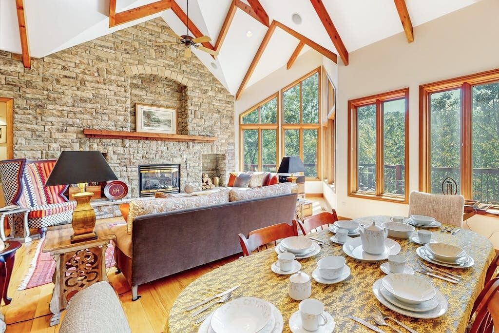 A spacious living room with a stone wall, a fireplace, and a dining area set for a meal.