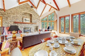 Ein großzügiges Wohnzimmer mit Steinwand, Kamin und Essbereich, der für eine Mahlzeit gedeckt ist.