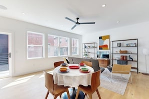 A dining area with a round table, chairs, and a ceiling fan. - 2BR Modern Townhouse with Balcony (Bentonville)