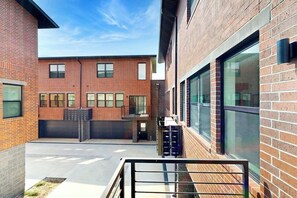 A courtyard with a brick building, large windows, and a metal gate. - 2BR Modern Townhouse with Balcony (Bentonville)