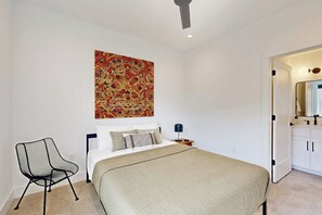 A bedroom with a bed, a chair, a nightstand, and a wall-mounted artwork. - 2BR Modern Townhouse with Balcony (Bentonville)