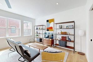 Een moderne woonkamer met een bank, een lange bank, een salontafel en een boekenkast.