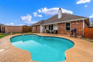 A residential backyard with a swimming pool, a barbecue grill, and a wooden fence. - 4BR with private pool, patio & firepit (Bentonville)