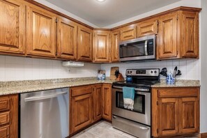 A kitchen with wooden cabinets, stainless steel appliances, and a granite countertop. - 4BR with private pool, patio & firepit (Bentonville)