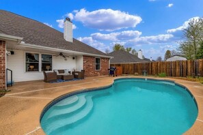 A residential backyard with a swimming pool, a covered patio, and a wooden fence. - 4BR with private pool, patio & firepit (Bentonville)