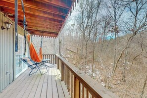Une terrasse en bois avec une rambarde, un fauteuil de relaxation et un hamac.