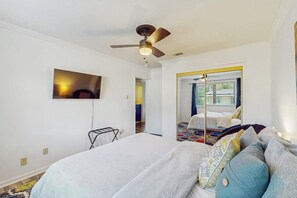 A hotel room with a bed, a ceiling fan, a TV mounted on the wall, and a view of the outside through a door. - 2BR Modern condo with shared hot tub & pool access (Hot Springs)