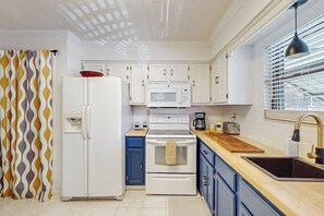 A kitchen with white appliances, blue cabinets, a wooden countertop, and a window with blinds. - 2BR Modern condo with shared hot tub & pool access (Hot Springs)