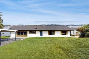 A single-story house with a flat roof, a covered porch, and a well-maintained lawn. - Sophisticated Waterfront Home with Private Dock (Hot Springs)