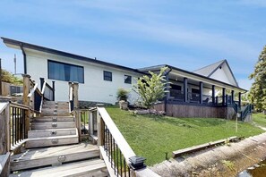 A modern two-story house with a covered porch and a wooden deck. - Sophisticated Waterfront Home with Private Dock (Hot Springs)