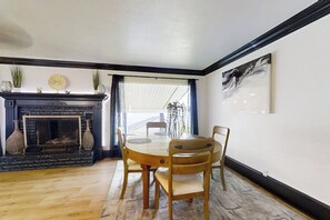 A dining area with a round table and chairs, a fireplace, and a painting on the wall. - Sophisticated Waterfront Home with Private Dock (Hot Springs)
