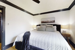 A bedroom with a large bed, two bedside lamps, a nightstand, and a painting on the wall. - Sophisticated Waterfront Home with Private Dock (Hot Springs)