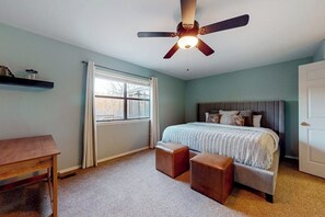 A bedroom with a bed, a ceiling fan, a window with curtains, a bedside table, and a door. - 2BR lakefront retreat with screened sunroom (Rogers)