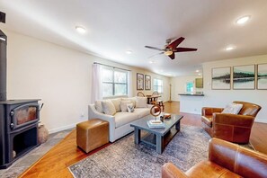 A living room with a fireplace, a sofa, a coffee table, and a ceiling fan. - 2BR lakefront retreat with screened sunroom (Rogers)