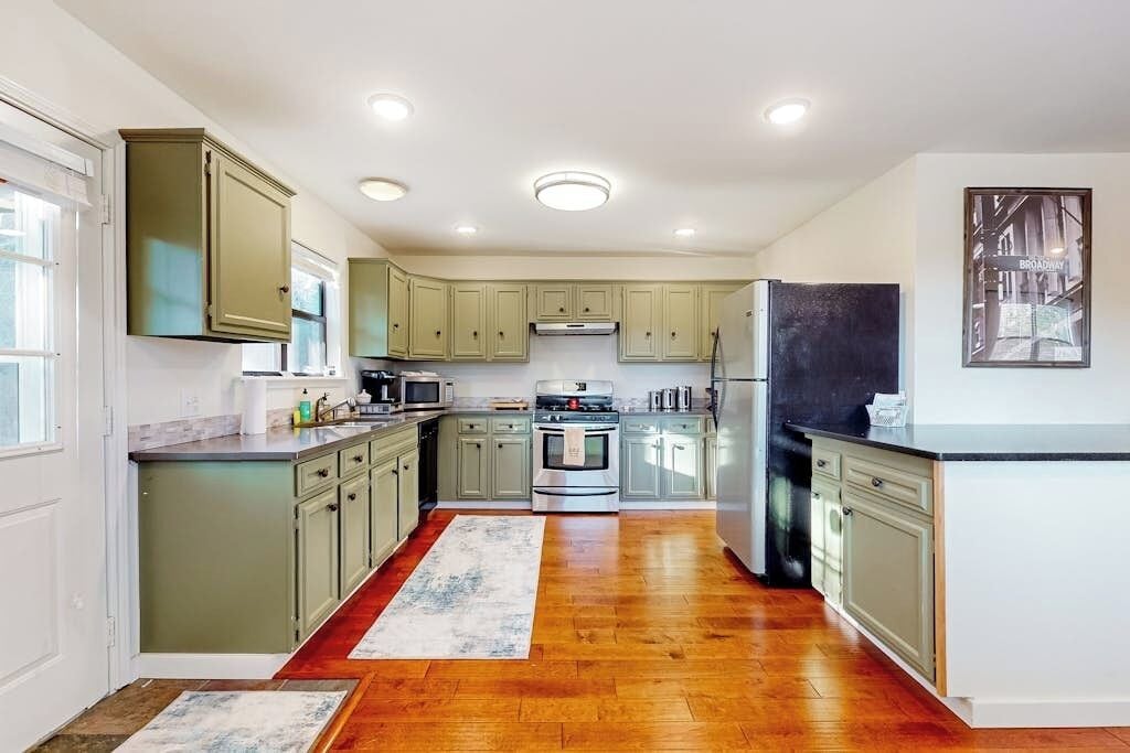 Una cocina con piso de madera, armarios empotrados, una isla central y un refrigerador.