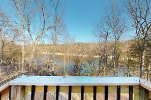 A wooden deck with a view of a lake and trees. - 2BR lakefront retreat with screened sunroom (Rogers)