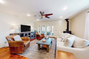 A living room with a sofa, armchair, coffee table, and a television. - 2BR lakefront retreat with screened sunroom (Rogers)