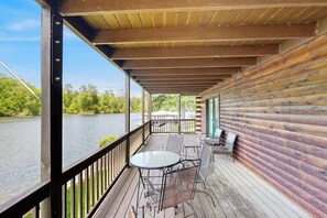 A covered deck with a table and chairs, overlooking a river. - 3BR Apartment - Riverfront - River Access - WIFI (Hot Springs)