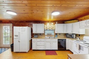 A kitchen with wooden ceiling, white cabinets, a refrigerator, a dishwasher, a microwave, and a stove. - 3BR Apartment - Riverfront - River Access - WIFI (Hot Springs)