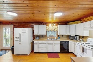 A kitchen with wooden ceiling, white cabinets, a refrigerator, a dishwasher, a microwave, and a stove. - 5BR Cabin - Riverfront - Fishing - WIFI - W&D (Hot Springs)