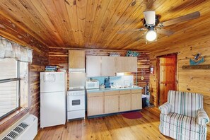 A compact kitchen with wooden cabinets, a refrigerator, a microwave, and a stove. - 5BR Cabin - Riverfront - Fishing - WIFI - W&D (Hot Springs)