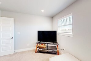 A room with a television on a stand, a door, and a window with blinds. - 4BR home with foosball & children's items, dogs ok (Bentonville)