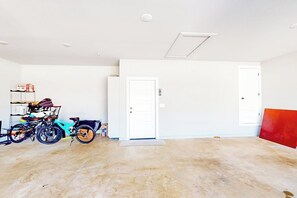 A spacious garage with two white doors, a concrete floor, and a bicycle rack with a bicycle. - 4BR home with foosball & children's items, dogs ok (Bentonville)