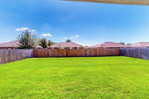 A fenced backyard with a well-maintained lawn and a wooden fence. - 4BR home with foosball & children's items, dogs ok (Bentonville)