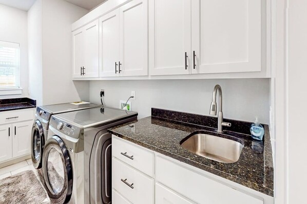A laundry area with a washing machine, a sink, and cabinets. - 4BR home with foosball & children's items, dogs ok (Bentonville)