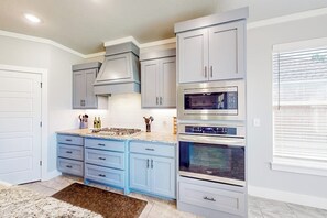 A kitchen with light blue cabinets, a granite countertop, and stainless steel appliances. - 4BR home with foosball & children's items, dogs ok (Bentonville)