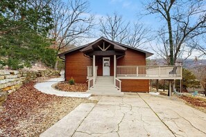 A wooden cabin with a porch, a stone pathway, and a view of trees and mountains. - 2BR Peaceful Retreat with Lake Views, Deck & W&D (Garfield)