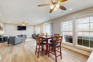 A spacious living area with a dining table and chairs, a sofa, and a television mounted on the wall. - 2BR Peaceful Retreat with Lake Views, Deck & W&D (Garfield)
