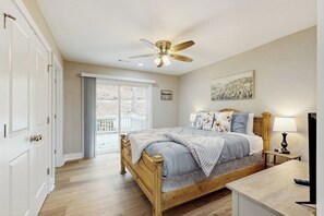 A bedroom with a wooden bed, a ceiling fan, a nightstand with a lamp, and a window with curtains. - 2BR Peaceful Retreat with Lake Views, Deck & W&D (Garfield)