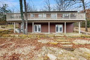 A two-story cabin with a balcony, stone foundation, and a wooded backdrop. - 2BR Peaceful Retreat with Lake Views, Deck & W&D (Garfield)