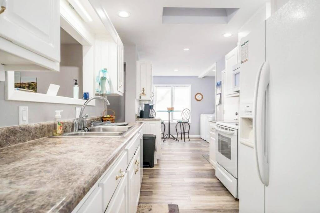 A modern kitchen with white cabinets, a granite countertop, and a central island with a sink.
