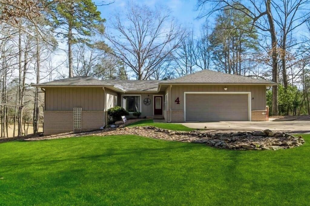 Une maison de plain-pied avec un garage, un porche à l’avant et une pelouse bien entretenue.