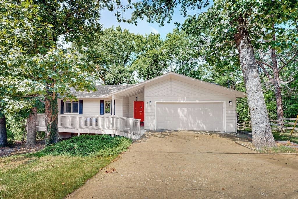 A single-story house with a garage, surrounded by trees.