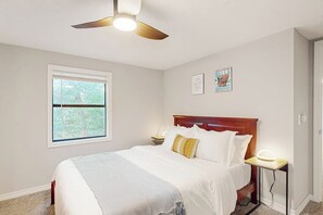 A bedroom with a bed, a nightstand, a ceiling fan, a window, and wall art. - 3BR dog-friendly with decks, foosball, & views (Bella Vista)