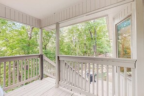 A covered porch with a white railing, overlooking a wooded area. - 3BR dog-friendly with decks, foosball, & views (Bella Vista)