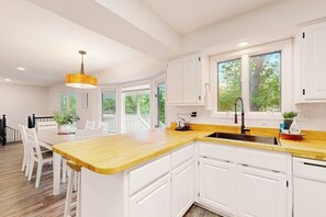 A modern kitchen with white cabinetry, a wooden countertop, and a large window providing natural light. - 3BR dog-friendly with decks, foosball, & views (Bella Vista)