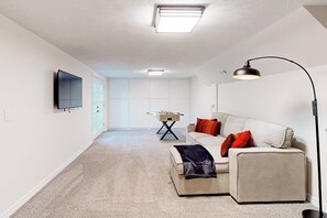 A modern living room with a sofa, a coffee table, a TV mounted on the wall, and a floor lamp. - 3BR dog-friendly with decks, foosball, & views (Bella Vista)
