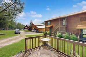 A wooden cabin with a deck, outdoor seating, and a staircase leading to a second floor. - 1BR Condo - Riverfront - Fishing - Full Kitchen (Hot Springs)