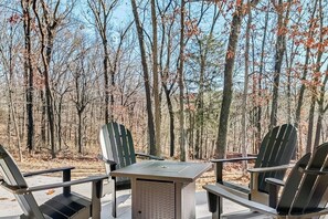 An outdoor seating area with a table and chairs, surrounded by trees. - The Dutchman | 4BR, Deck, Firepit & Fireplace (Bella Vista)
