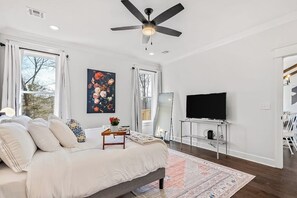 A bedroom with a bed, a ceiling fan, a TV, and a large window. - The Dutchman | 4BR, Deck, Firepit & Fireplace (Bella Vista)