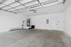 A spacious, empty room with a concrete floor, a white door, and a ceiling with fluorescent lighting. - The Dutchman | 4BR, Deck, Firepit & Fireplace (Bella Vista)