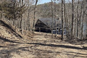 A rustic cabin with a dirt path leading to it, surrounded by trees. - 4BR Waterfront - Screen-in Deck (Eureka Springs)