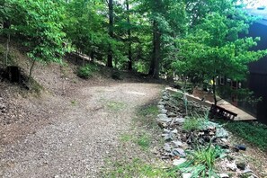 A gravel path leading through a wooded area with a stone wall on one side and a building with a sloped roof on the other. - 4BR Waterfront - Screen-in Deck (Eureka Springs)